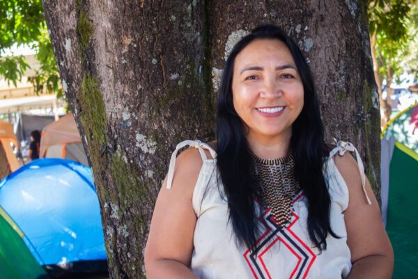 Retrato de Marilane sorrindo e  usando um vestido tradicional Kokama. Marilane tem cabelos longos, lisos e pretos e pele indígena.