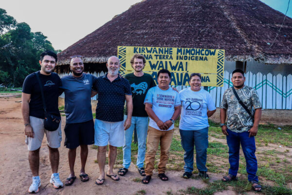 Indígenas Wai Wai junto a equipe da ACT-Brasil em frente a local de realização do Intercâmbio na Aldeia Anauá