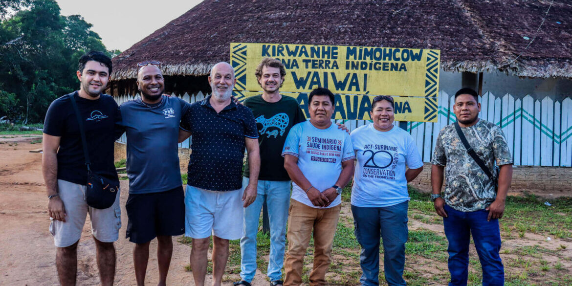 Indígenas Wai Wai junto a equipe da ACT-Brasil em frente a local de realização do Intercâmbio na Aldeia Anauá